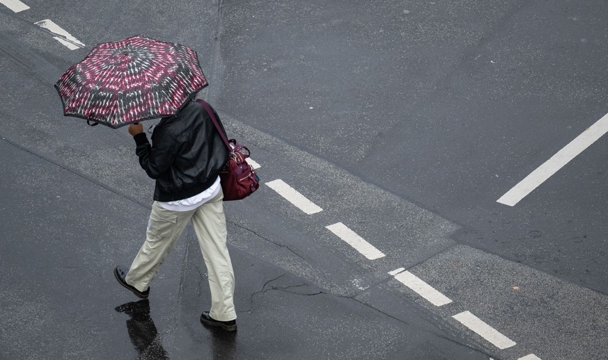 ARCHIV - 13.11.2023, Hessen, Frankfurt/Main: Eine Passantin geht bei Regen über die Straße. (zu dpa: «Trübes Wetter in Hessen - ab Mittwoch Regen») Foto: Boris Roessler/dpa +++ dpa-Bildfunk +++