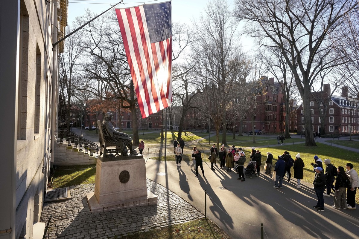 FILE - People take photos near a John Harvard statue, left, on the Harvard University campus, Jan. 2, 2024, in Cambridge, Mass. In a letter Monday, Feb. 19, to the school community, Harvard University ...