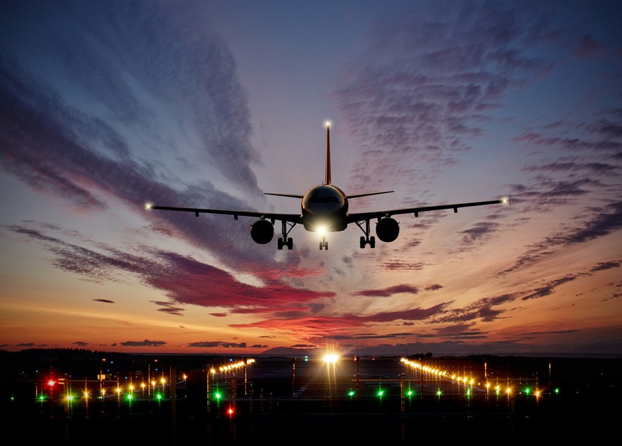 Passengers commercial airplane landing on runway with dramatic sunset sky. Concept of fast travel