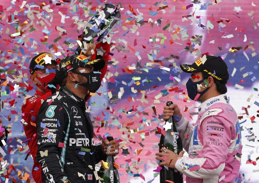 Third placed Ferrari driver Sebastian Vettel of Germany, left, pours champagne of race winner Mercedes driver Lewis Hamilton of Britain, as Racing Point driver Sergio Perez, right, of Mexico who finis ...