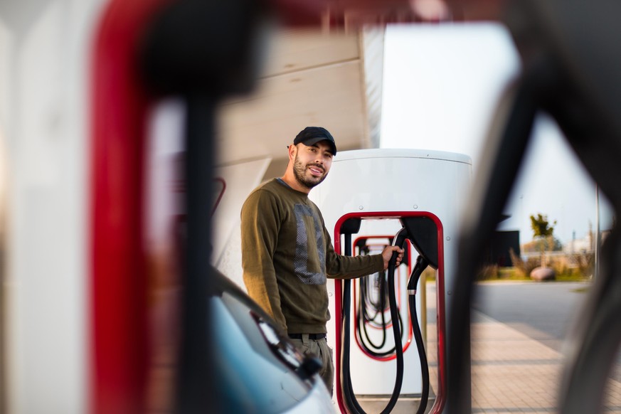 Man pours fuel into his car. Focus is on man. Electric pump for car.