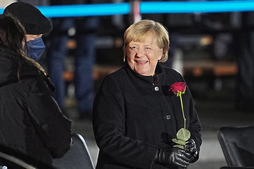 dpatopbilder - 02.12.2021, Berlin: Bundeskanzlerin Angela Merkel (CDU) lacht nach ihrer Verabschiedung durch die Bundeswehr mit einer Rosen in der Hand neben ihrem Mann, Joachim Sauer. Mit einem Gro