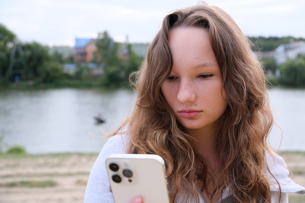 Child Playing on Smartphone in Park, Kid Browsing Internet on Smart Phone, Blonde Teenager Girl Typing Messages Talking on Device. Pretty Caucasian girl texting on mobile phone outdoors. xkwx device y ...