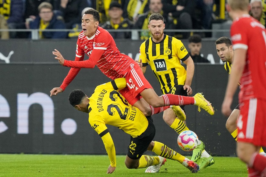 Bayern&#039;s Jamal Musiala falls over Dortmund&#039;s Jude Bellingham during the German Bundesliga soccer match between Borussia Dortmund and Bayern Munich in Dortmund, Germany, Saturday, Oct. 8, 202 ...