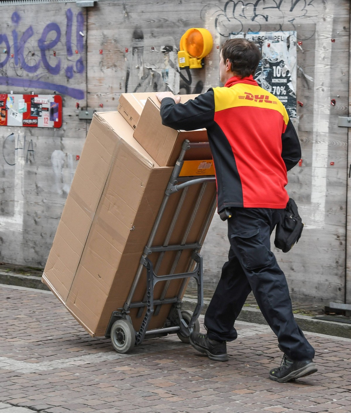 Ein Paketbote transportiert in Freiburg mit einer Karre Pakete . DHL-Paketzustellung in der Vorweihnachtszeit in Freiburg. *** A parcel carrier transports parcels in Freiburg with a trolley DHL parcel ...