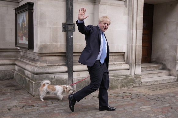 FILE - Britain&#039;s Prime Minister Boris Johnson waves at the media as he leaves with his dog Dilyn after voting at a polling station in London, for local council elections, Thursday, May 5, 2022. T ...