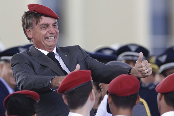 FILE - In this April 19, 2018 file photo, presidential hopeful, conservative Brazilian lawmaker Jair Bolsonaro flashes two thumbs up as he poses for a photo with cadets during a ceremony marking Army  ...