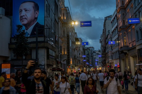 ISTANBUL, TURKEY - JUNE 18: People walk on Istanbul&#039;s famous Istiklal shopping street under a large election poster showing the portrait of Turkey&#039;s President Recep Tayyip Erdogan on June 19 ...