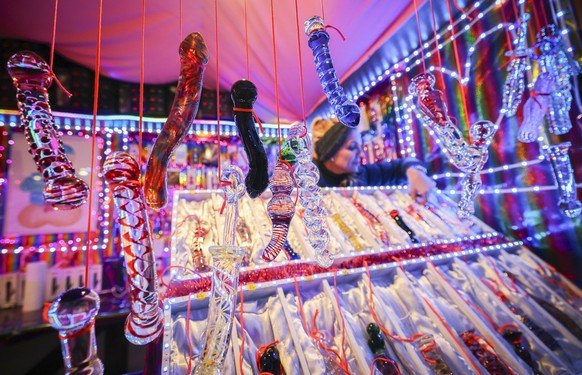 13.11.2023, Hamburg: Glasdildos hängen am Eröffnungstag an einem Verkaufsstand mit dem Namen &quot;Warm feucht und lecker&quot; auf dem &quot;Santa Pauli&quot; Weihnachtsmarkt auf dem Spielbudenplatz. ...