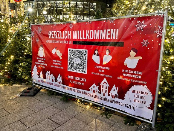 Ein Schild am Eingang des Weihnachtsmarktes am Breitscheidplatz erinnert an die geltenden Maßnahmen: Maskenpflicht.