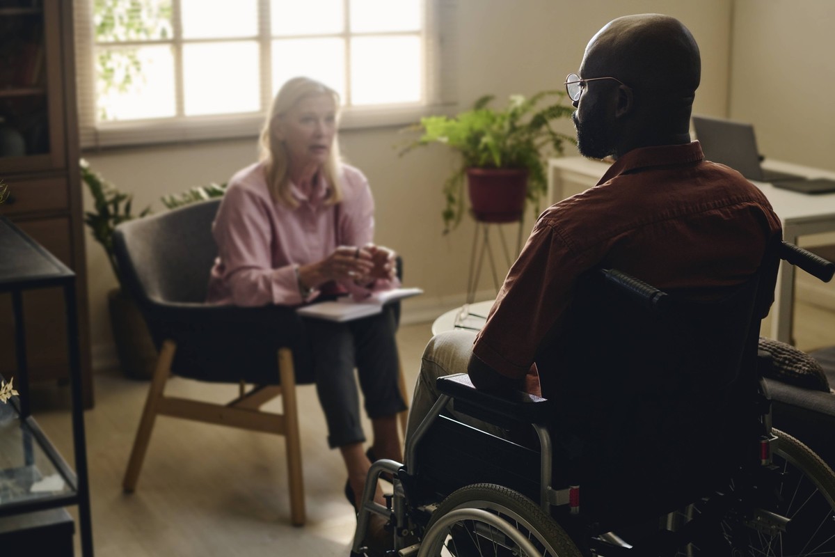 Psychologist discussing with patient sitting on wheelchair at office model released, Symbolfoto property released, DSHF00753
