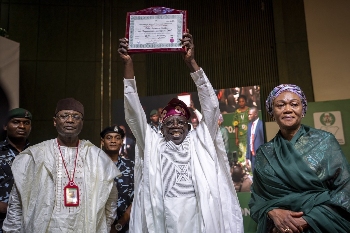 FILE- President-Elect Bola Tinubu, center, displays his certificate, accompanied by his wife Oluremi Tinubu, right, and chairman of the Independent National Electoral Commission (INEC) Mahmood Yakubu, ...