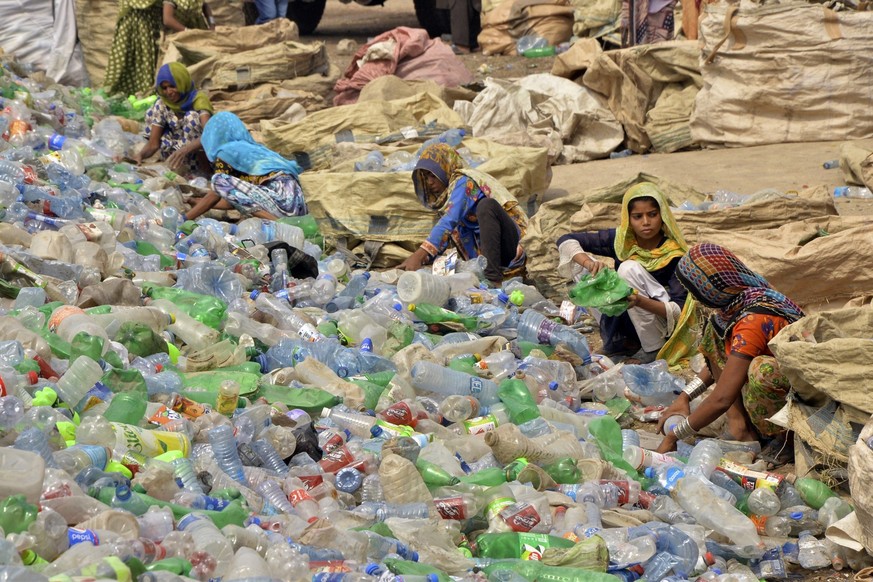ARCHIV - 30.04.2023, Pakistan, Hyderabad: Pakistanische Arbeiter, meist Frauen, sortieren leere Flaschen in einer Plastikrecyclingfabrik in Hyderabad, Pakistan. Weltweit wird mehr und mehr Plastik pro ...