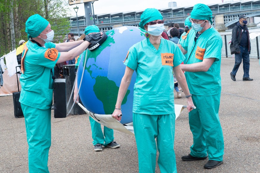 Climate Change Activists Extinction Rebellion (XR) 'planet doctors' stage a fake CPR procedure and fake electro shock the earth as they host an Outreach Day, hosting workshops and speakers outside of  ...