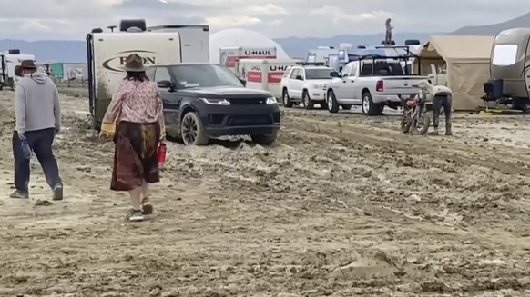 HANDOUT - 04.09.2023, USA, Black Rock: In diesem Bild aus einem von Rebecca Barger zur Verfügung gestellten Video laufen Menschen durch den Schlamm auf auf dem Gelände des Festivals «Burning Man». Nac ...