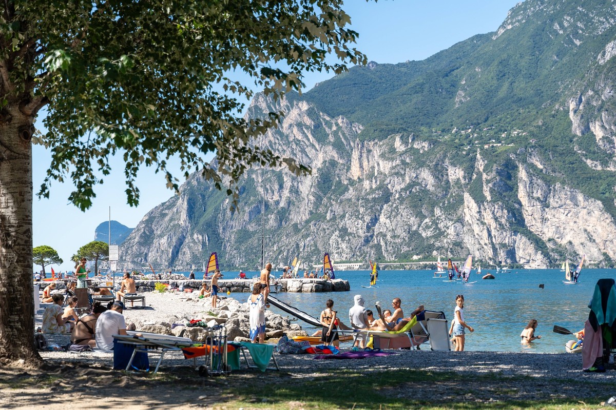 Torbole, Lake Garda, Italy - 7 August 2023: Vacation on Lake Garda, numerous tourists and vacationers sunbathe on the northern beach and swim in the lake *** Urlaub am Gardasee, zahlreiche Touristen u ...