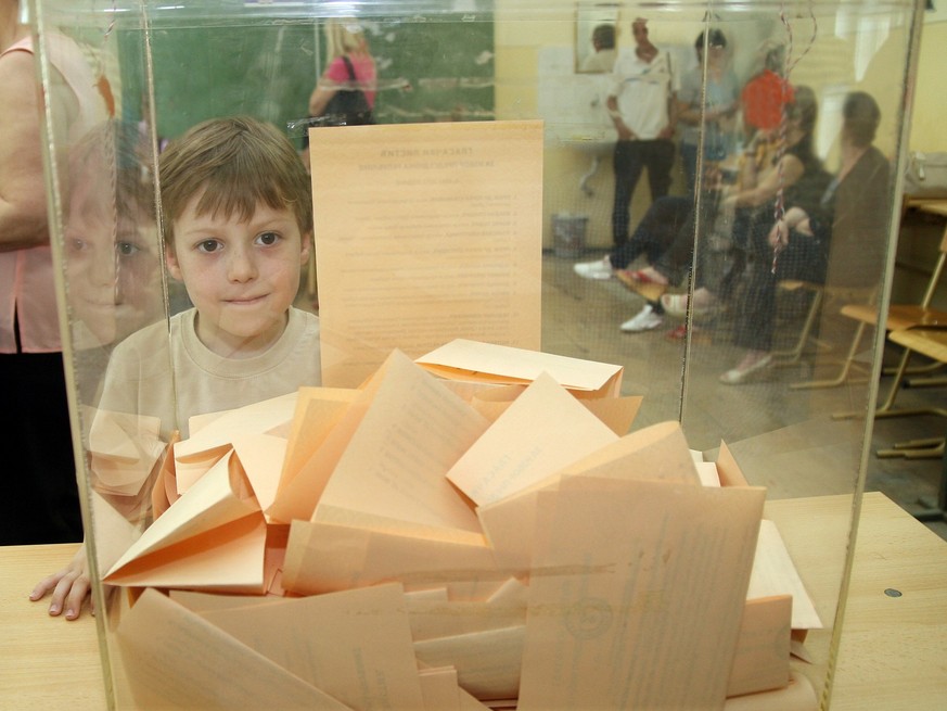 The boy looks at the ballot paper in the ballot box in elections