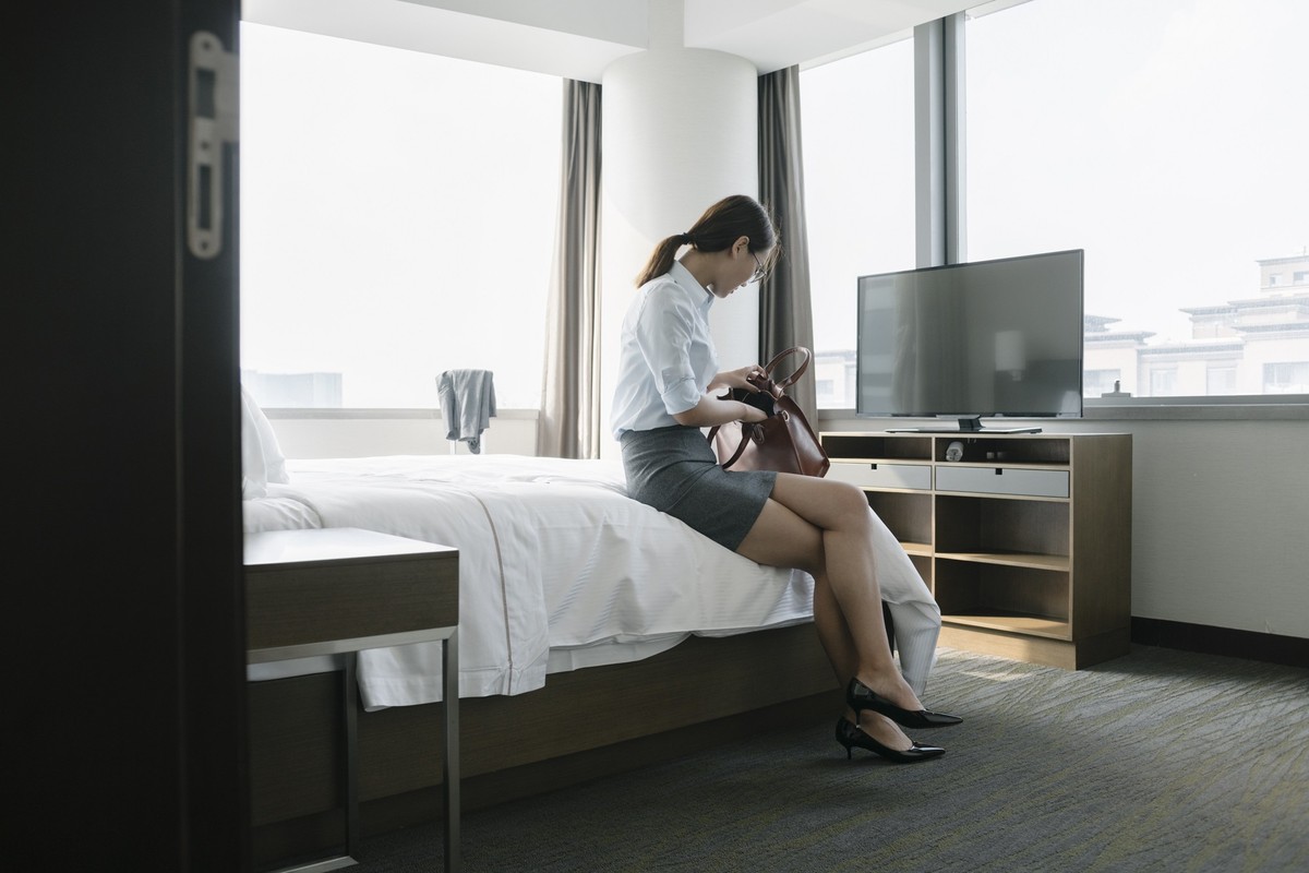 young business woman is looking for something in her handbag at hotel hoom.