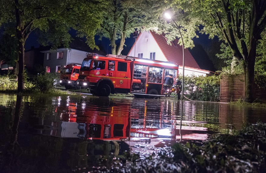 Feuerwehrleute pumpen in Hamburg-Lohbrügge nach einem Unwetter mit starkem Regen Wasser ab.