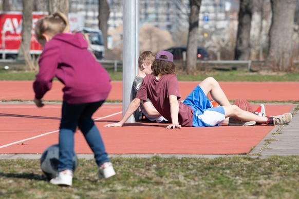 ARCHIV - 18.03.2020, Sachsen, Dresden: Ein Kind und zwei Jugendliche stehen und sitzen auf einem Sportplatz. Die Stimmung unter Jugendlichen hat sich einer Umfrage zufolge eingetr�bt. Zwar ist die gro ...