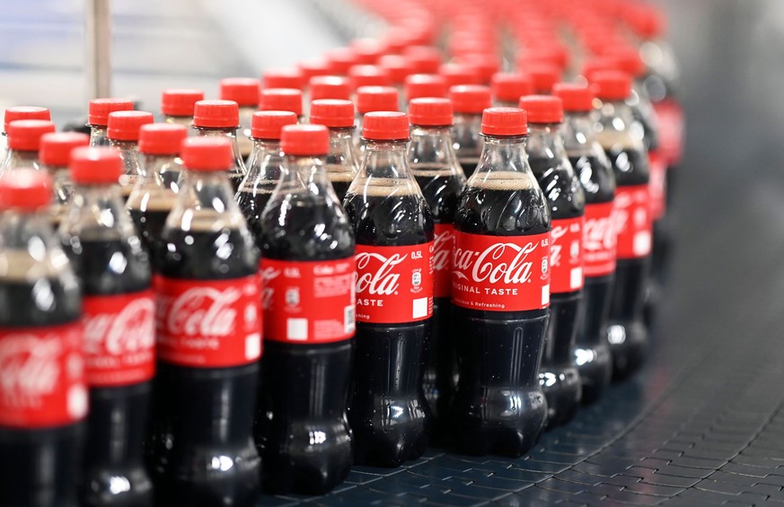 ARCHIV - 04.08.2023, Baden-Württemberg, Mannheim: Am Produktionsstandort Mannheim von Coca-Cola Europacific Partners - CCEP Deutschland GmbH werden abgefüllte 0,5 Liter Einweg Coca-Cola Flaschen über  ...