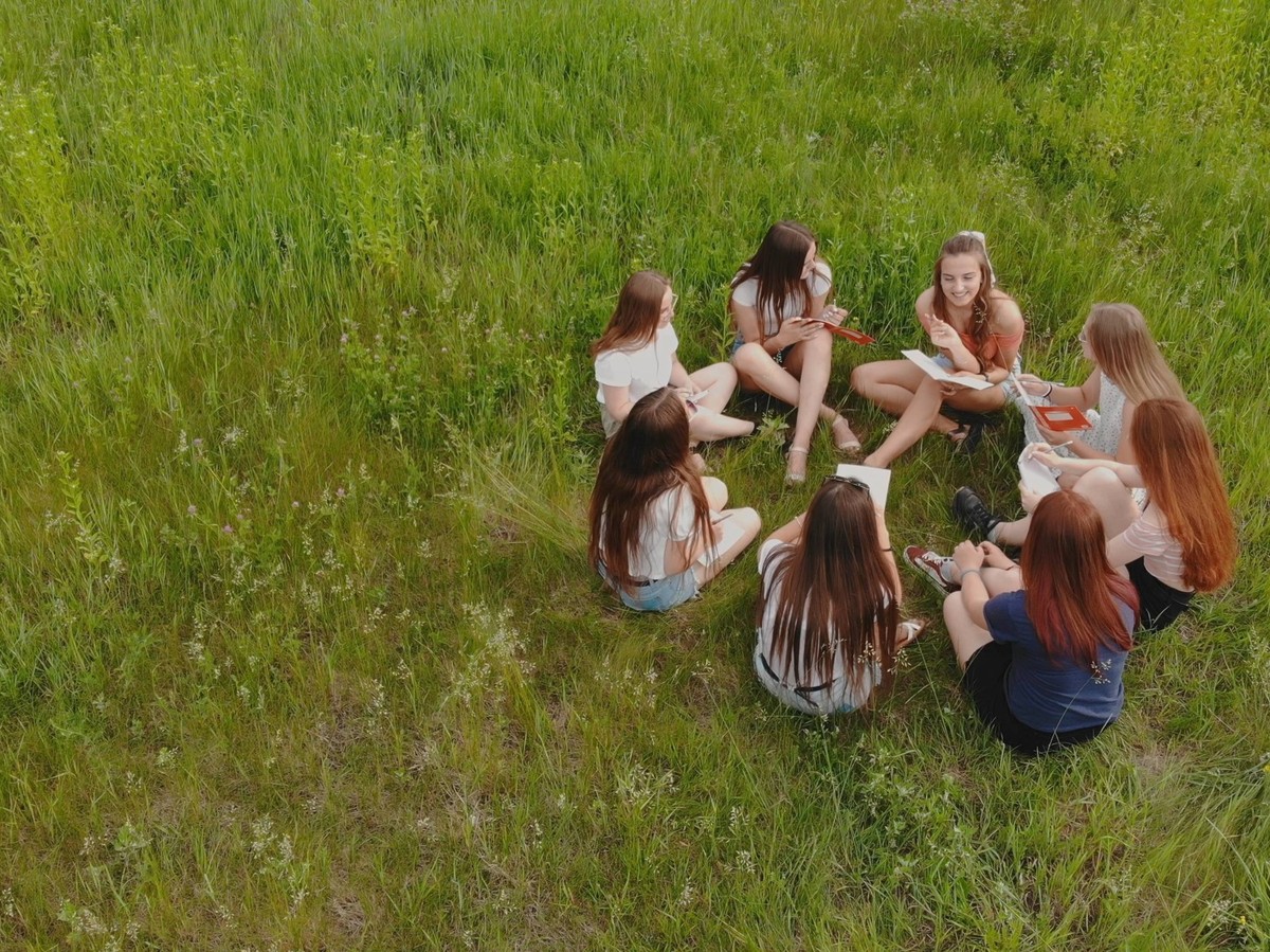Teamwork concept. A group of female student girls are sitting on the grass and solving problems. Teamwork concept. A group of female student girls are sitting on the grass and solving problems, model  ...