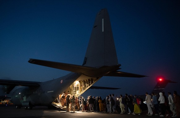Handout photo of French special forces escort Afghan refugees as they board a French Air Force Airbus A400M aircraft at Kabul airport, Afghanistan on August 23, 2021. Photo by Etat Major des Armees vi ...