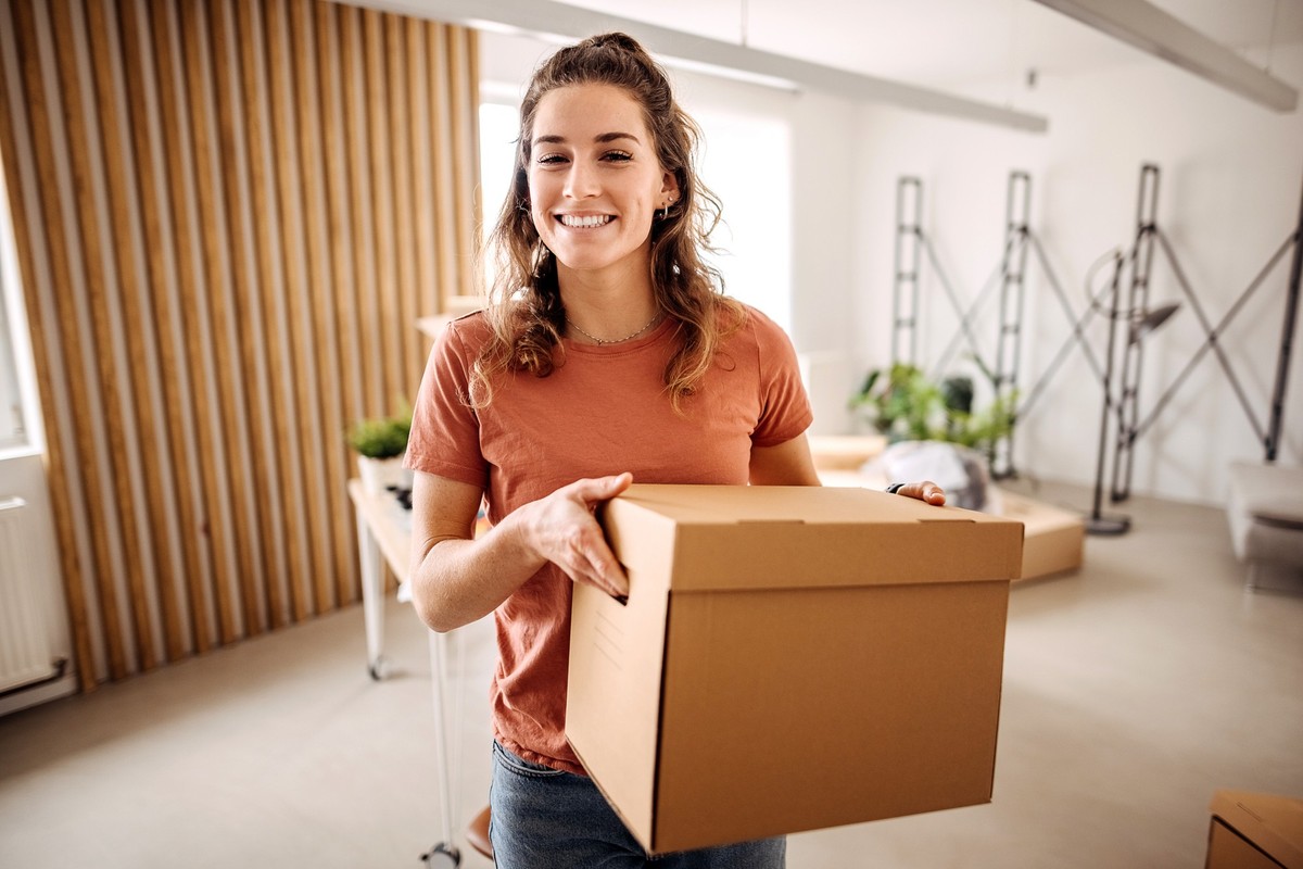 Young beautiful woman holds a box in her hands in her new apartment
