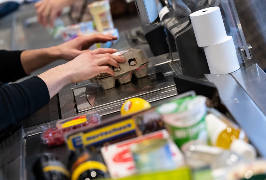 ARCHIV - 18.01.2023, Bayern, Neubiberg: Ein Kassierer scannt in einem Supermarkt an der Kasse die Produkte. Wie sich die Inflation in Deutschland im M