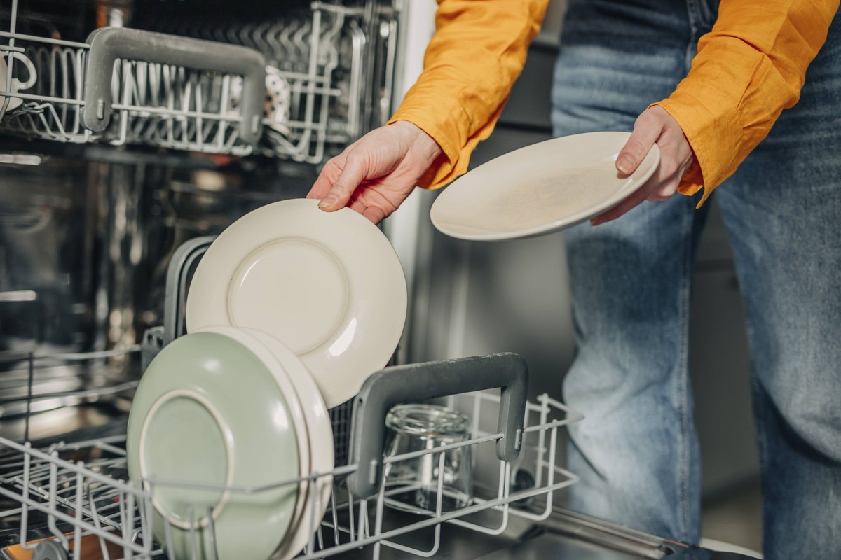 Woman unloading washed plates from dishwasher at home model released, Symbolfoto property released, VSNF01773