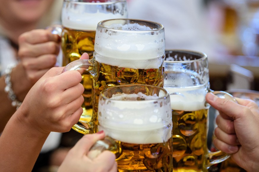 ARCHIV - 21.09.2019, Bayern, München: Besucherinnen prosten sich beim Auftakt zum Oktoberfest im Paulaner-Festzelt mit ihrer ersten Maß Bier zu. Bus und Bahn fahren ohne Maske - das war viele Monate l ...