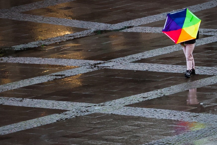 dpatopbilder - 13.01.2023, Hamburg: Eine Frau geht mit ihrem vom Sturm umgeschlagenen Regenschirm über den Rathausplatz in der Innenstadt. Foto: Christian Charisius/dpa +++ dpa-Bildfunk +++
