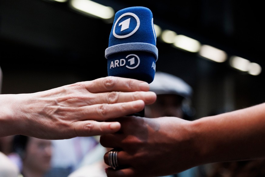 ARCHIV - 06.06.2023, Berlin: Eine Besucherin überreicht ein ARD-Mikrofon im ARD Perspective Lab während der Digital-Konferenz «Republica». Die ARD-Reform zu mehr Programmzusammenarbeit zwischen den Hä ...