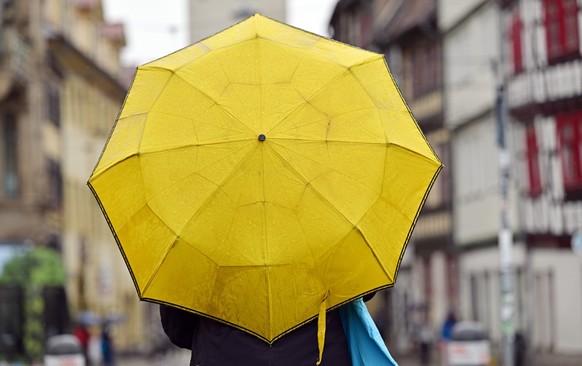 ARCHIV - 27.07.2023, Th�ringen, Erfurt: Eine Frau h�lt einen Regenschirm. (zu dpa: �Regen und teilweise Gewitter in Hessen�) Foto: Martin Schutt/dpa +++ dpa-Bildfunk +++