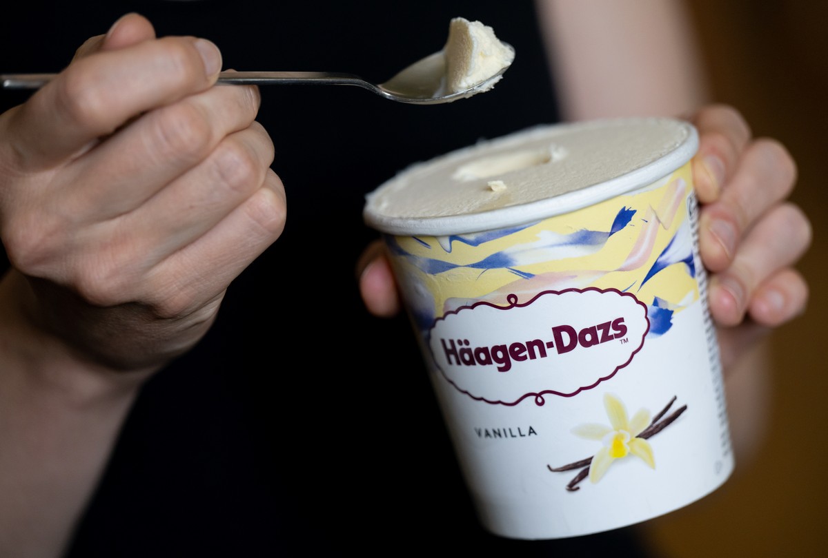 14.07.2022, Bayern, M�nchen: Eine Frau h�lt einen L�ffel und einen Becher Eis &quot;Vanilla&quot; von H�agen-Dazs in den H�nden. Der Hersteller General Mills ruft Produkte von H�agen-Dazs mit der Gesc ...