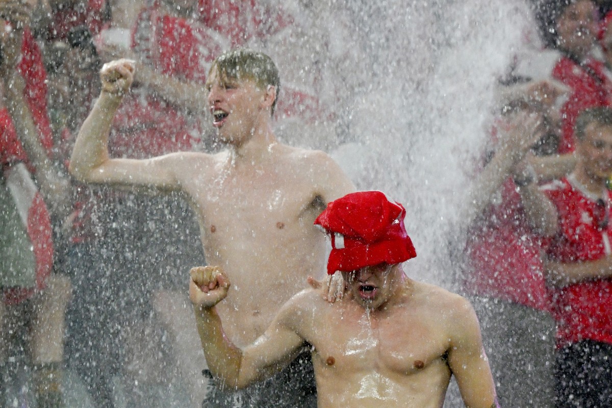 29.06.2024, Nordrhein-Westfalen, Dortmund: Fu�ball: EM, Deutschland - D�nemark, Finalrunde, Achtelfinale, Fans von D�nemark tanzen im Regen w�hrend einer Spielunterbrechung wegen schlechten Wetters. F ...
