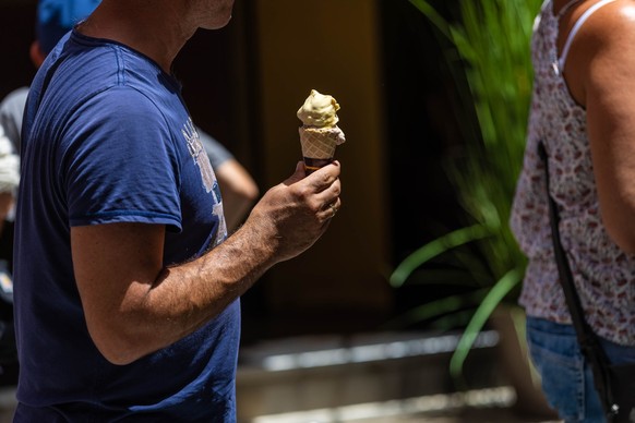 15.07.2023, Spanien, Mallorca: Ein Mann isst ein Eis. Am Ballermann wurden am Montag 36 Grad gemessen. Der vom nationalen Wetterdienst Aemet ausgerufene Hitze-Alarm galt am Montag in zwölf der insgesa ...