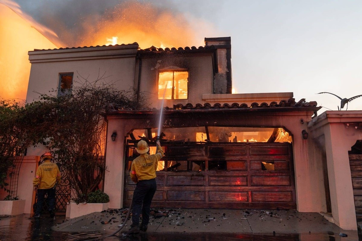 Syndication: Arizona Republic Firefighters attempt to extinguish a fire in a home along the Pacific Coast Highway in the Pacific Palisades neighborhood on Jan. 8, 2025. A wildfire broke out in Los Ang ...