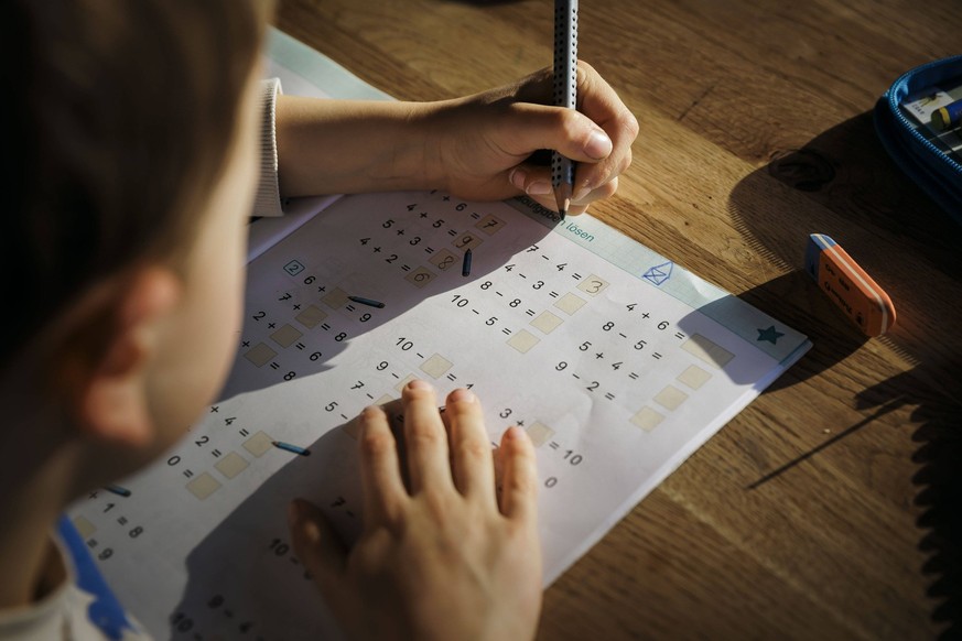 Ein sechsjaehriger Junge macht zu Hause Mathematik-Hausaufgaben der ersten Klasse in einem Arbeitsheft. Berlin, 13.03.2024. Berlin Deutschland *** A six-year-old boy does first grade math homework at  ...