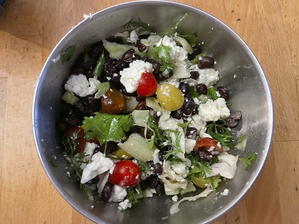 This image shows a salad made with half-can of black beans, feta cheese, celery, scallions, cilantro, cherry tomatoes and cabbage. (Beth J. Harpaz via AP)