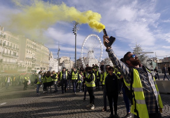 Demonstrators, known as they yellow jackets, protest in Marseille, southern France, Saturday, Dec. 1, 2018, against rising fuel costs and what they claim were dilapidated residential buildings that co ...