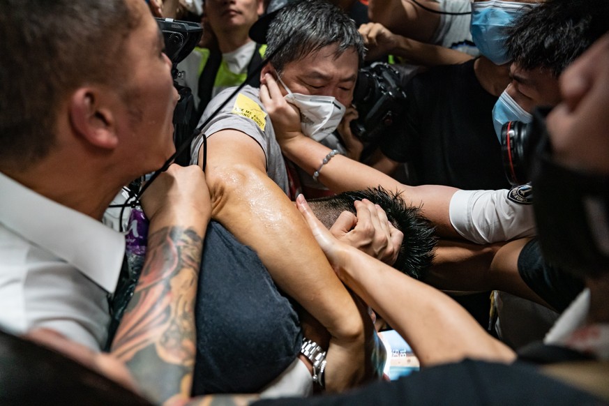 HONG KONG, CHINA - AUGUST 13: A man, who was suspected by protestors of being an undercover police officer, is surrounded by protesters at the Hong Kong International Airport during a demonstration on ...