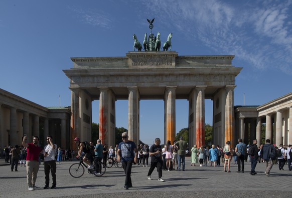 17.09.2023, Berln, Berlin: Menschen sind am Brandenburger Tor unterwegs, das Mitglieder der Klimaschutzgruppe Letzte Generation am Sonntagvormittag mit oranger Farbe angesprüht haben. Die Polizei nahm ...