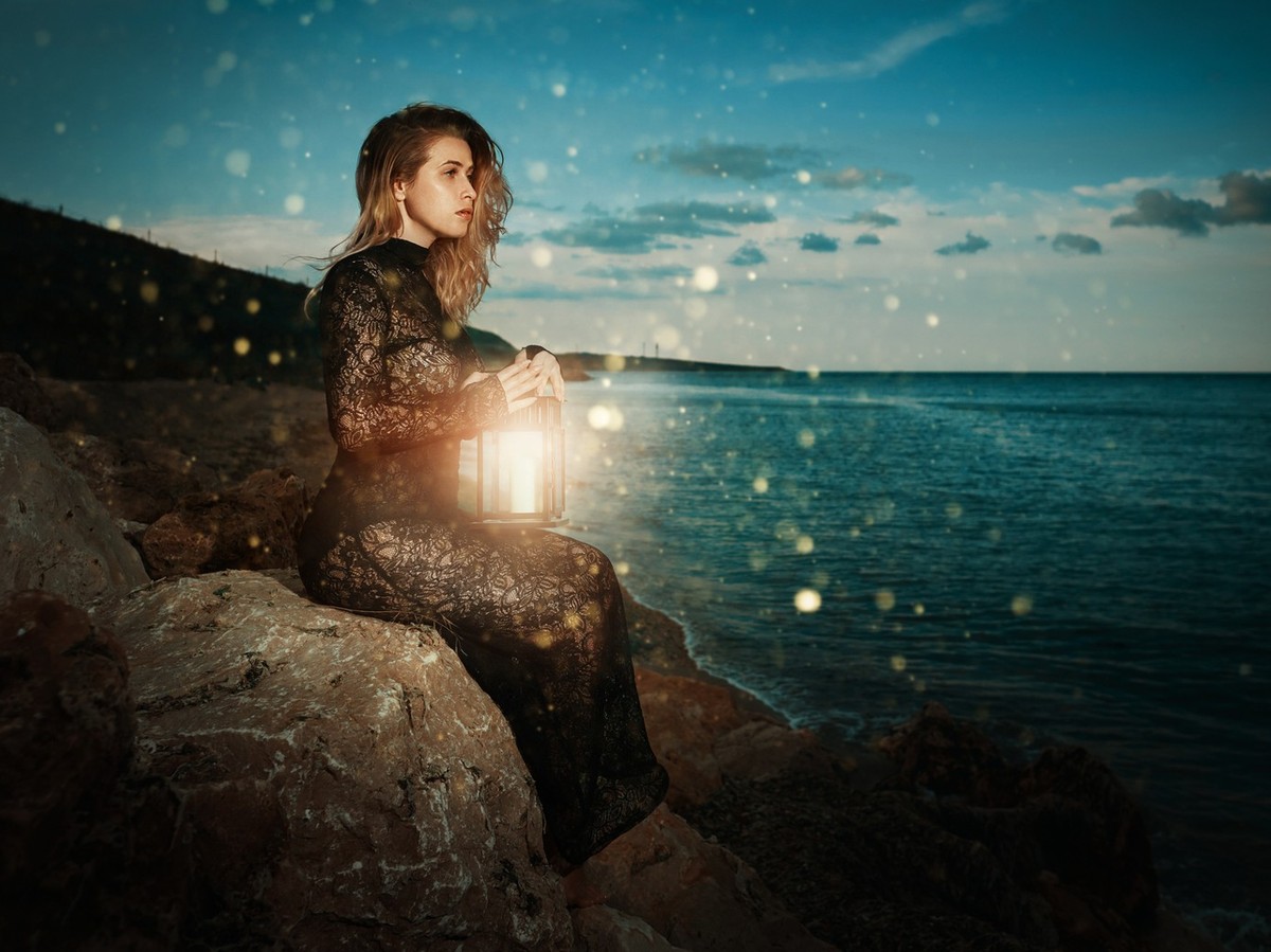magician woman with lamp looking at the sea far away, thinking at her spell,