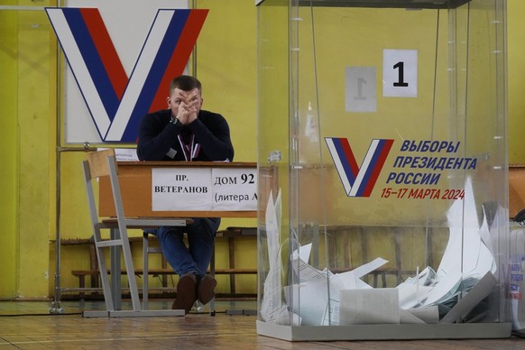 15.03.2024, Russland, St. Petersburg: Ein Mitglied einer Wahlkommission wartet auf Wähler in einem Wahllokal während der Präsidentschaftswahlen. ach einer von Manipulationsvorwürfen begleiteten Präsid ...