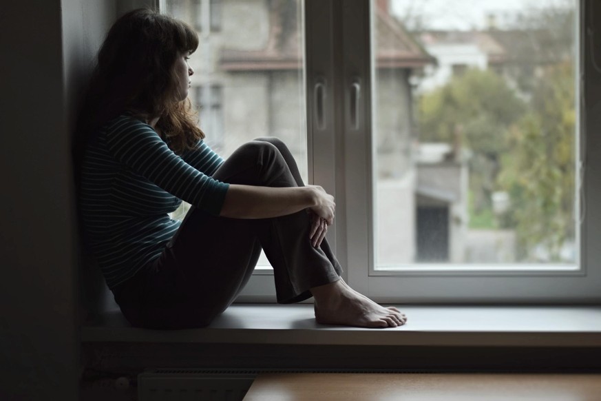 Traurige Frau sitzt am Fenster.