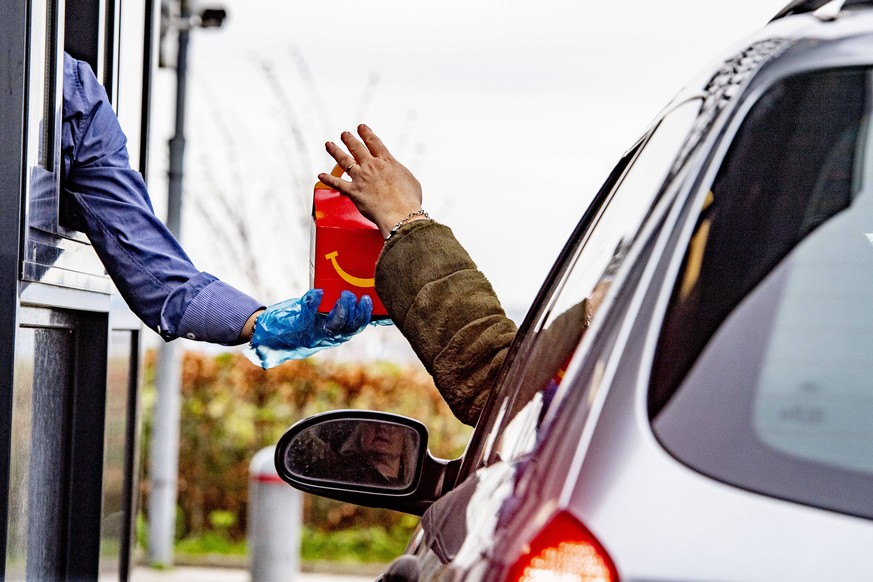 March 18, 2020, Schiphol, Netherlands: An employee wearing gloves as a protection seen giving food to a costumer at a McDonald s Mac Drive amid Coronavirus Covid-19 fear..Netherlandss Health Ministry  ...