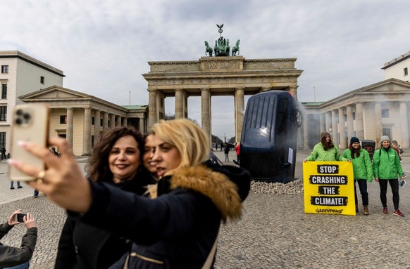 BERLIN, GERMANY - MARCH 22: People take a selfie with an installation by Greenpeace activists showing an SUV that is seemingly rammed into the pavement in front of the Brandenburg Gate on March 22, 20 ...