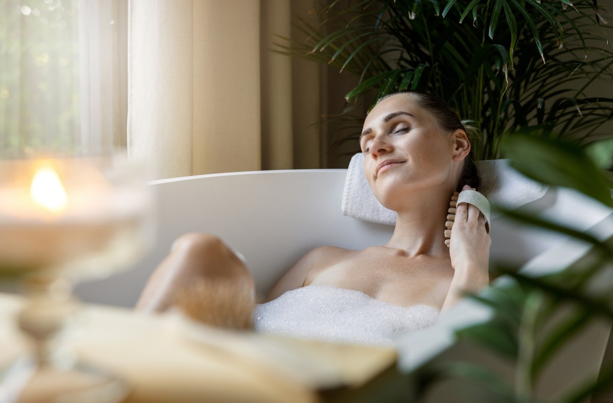 woman enjoying spa bath with foam and body massage brush