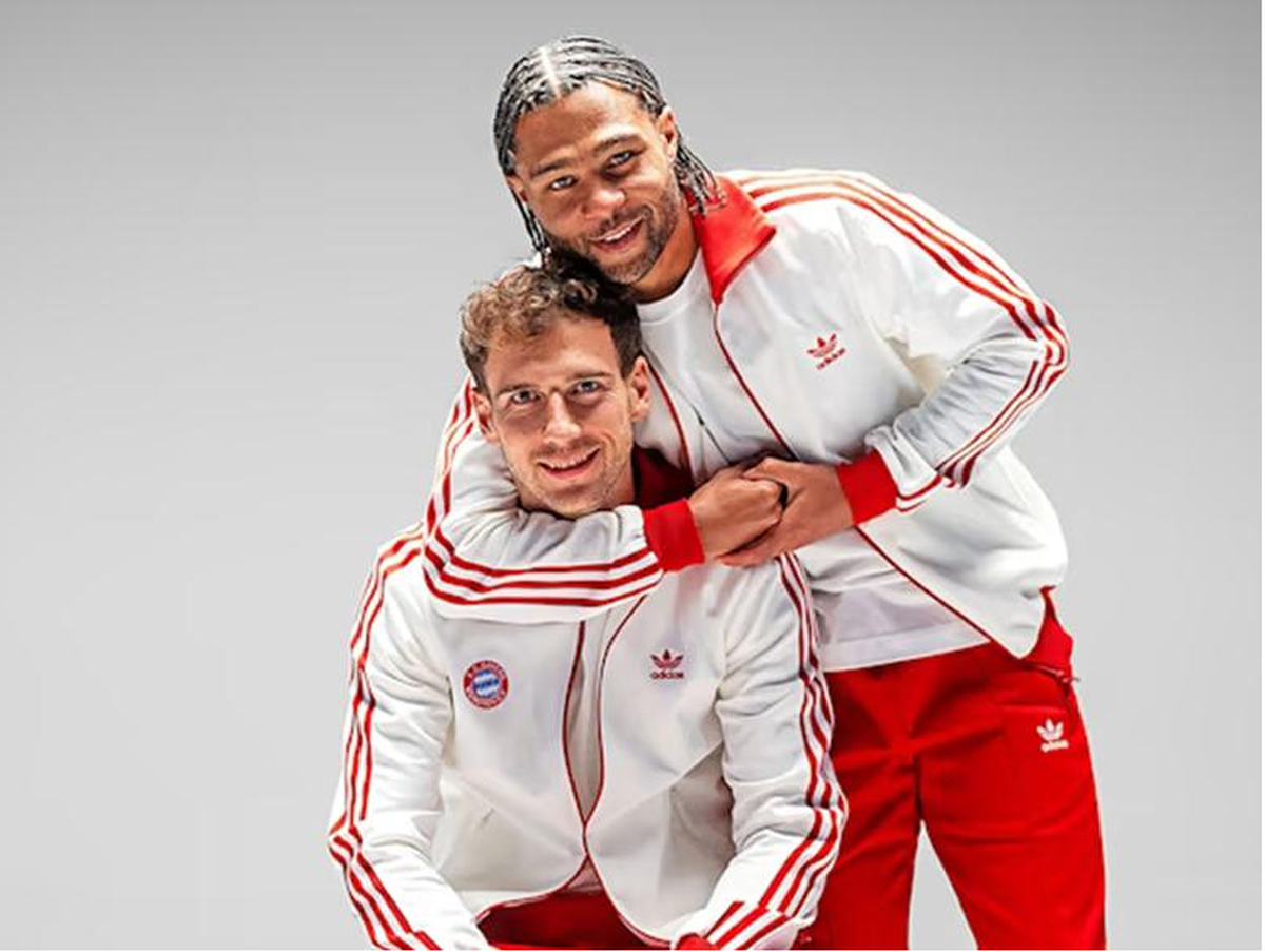 Serge Gnabry (rechts) und Leon Goretzka bewerben den Retro-Trainingsanzug.